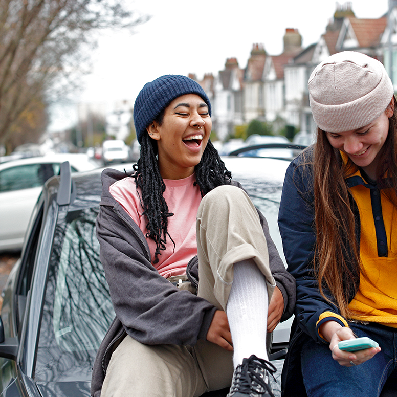 hero image for spring: teenagers relaxing on a london residential street, wearing trendy clothes and colourful beanie hats